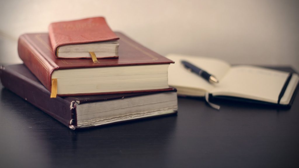 Stack of leather-bound books with a pen representing pre-death agreements