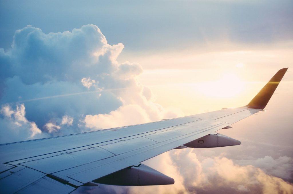 Aircraft wing above the clouds representing air, rail and maritime travel claims